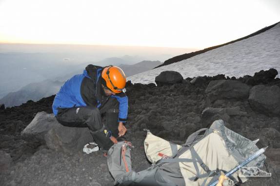 Amarrando os grampões nas botas para poder enfrentar a neve e gelo nas encostas do vulcão Lanín, na região de Junín de Los Andes, no sul da Argentina